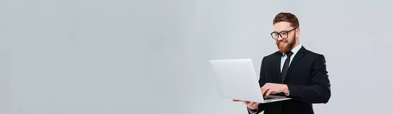 A SAP professional standing hoding a laptop and working on it with  a smiling face