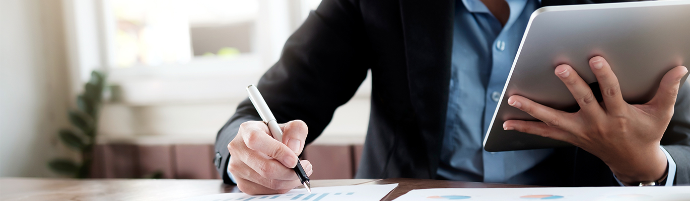 A business administrator reading E-documents and signing papers