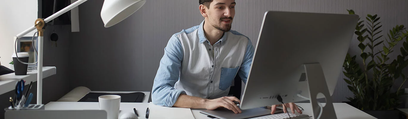 A graphic designer can be seen working on a desktop computer in his cabin.