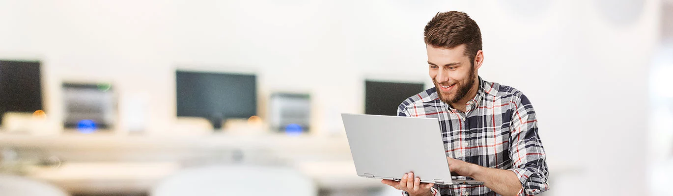 A Full Stack Developer with a laptop in hand, working on it with a smiling face