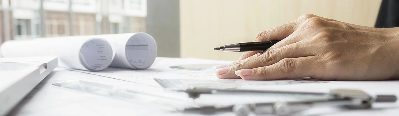 Hand of a Tekla professional placed on a paper holding a pen 