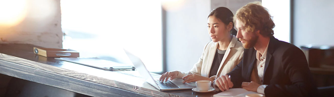 Two ACP professionals at workplace sitting infront of a laptop 