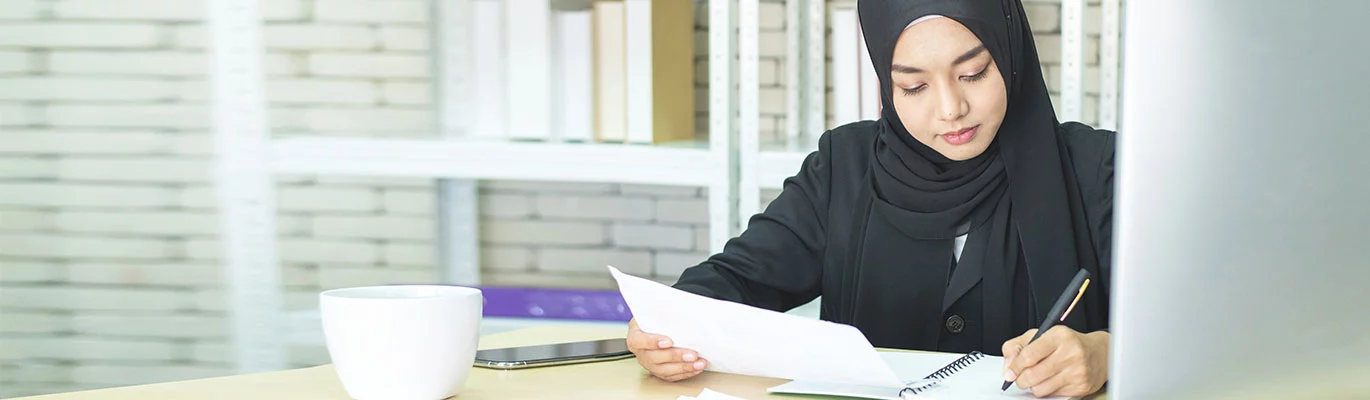 A Student in pardah with a pen in hand  learning Arabic language