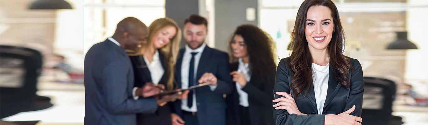 A Sap business one trainer standing infront holding her hands while four other trainers on discussion on SAP Business One Course
