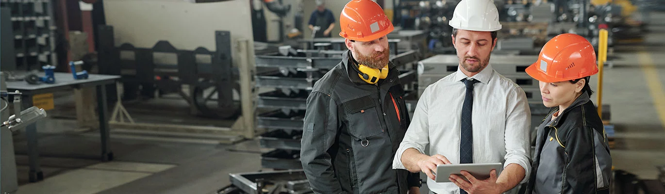 A SAP PM professional holding a tablet giving instruction to trainees at work place