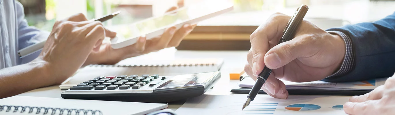 SAP FICO professionals doing financial operations with a calculator and records on table