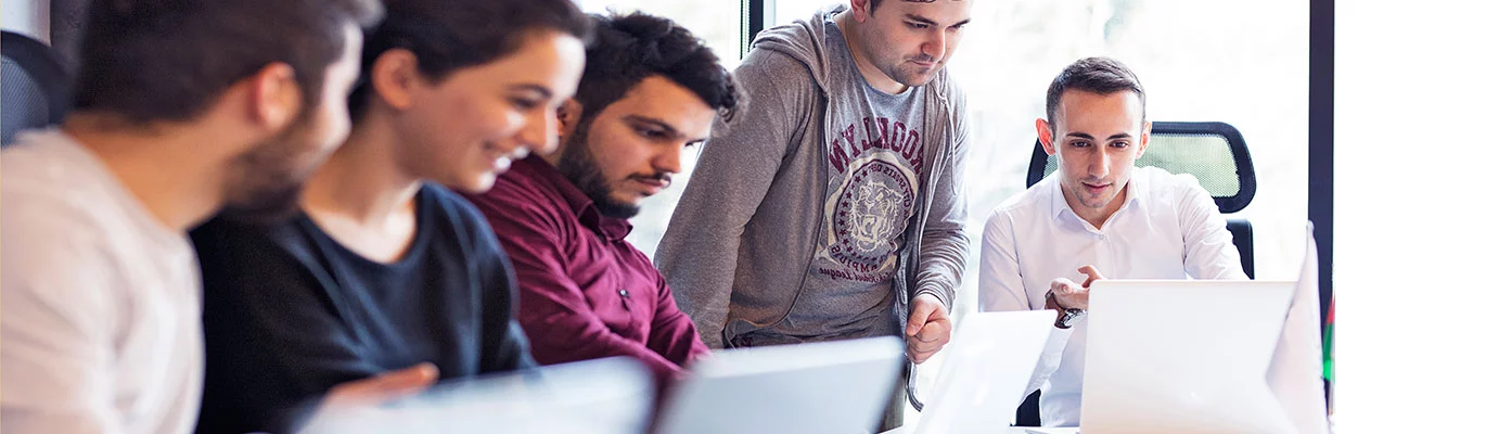 A group of five SQL Language students working in their laptops placed on a table. 