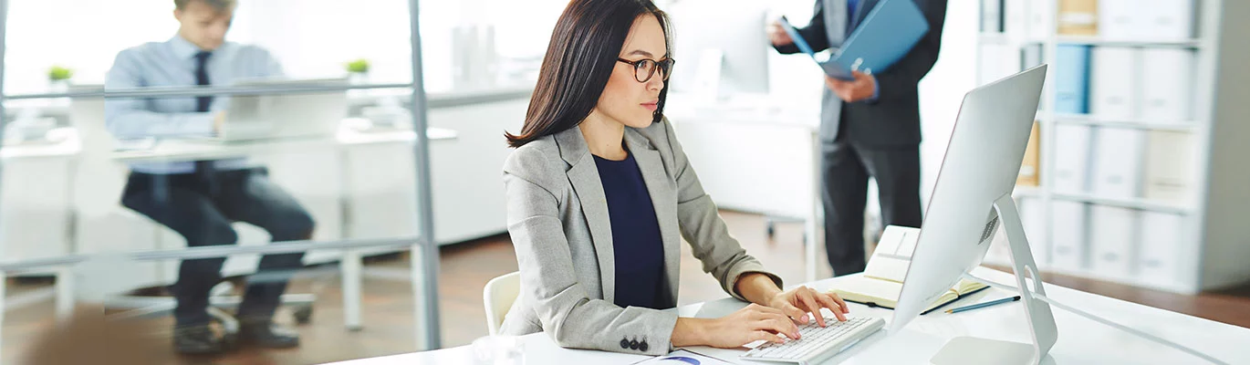 An office administrator can be seen working on desktop computer.