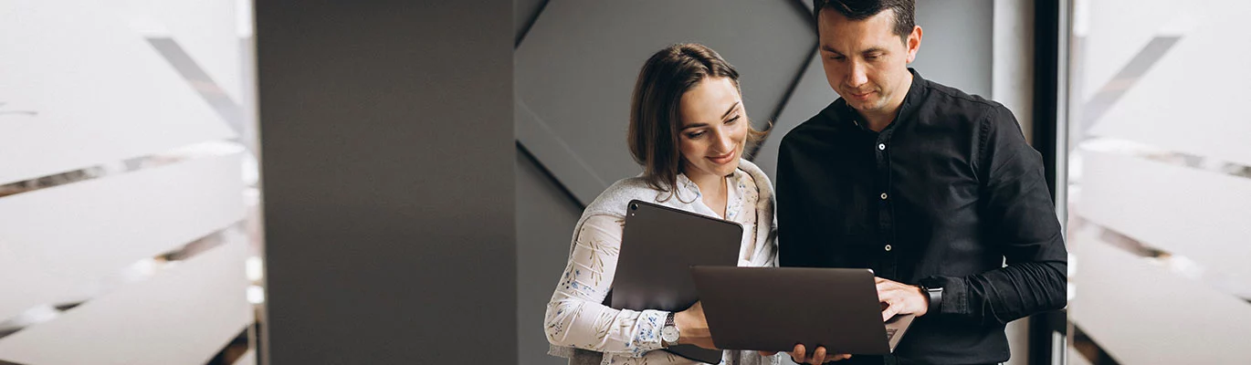 Two SQL Professionals in non-executive look discussing with laptops on their hands