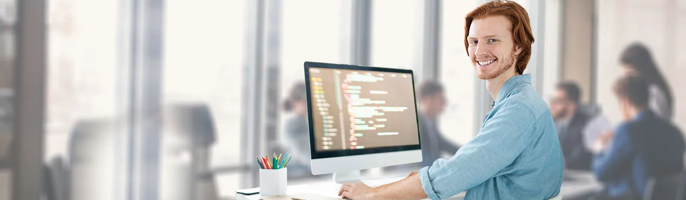 A PHP expert working on office computer, while other colleagues working behind can also seen