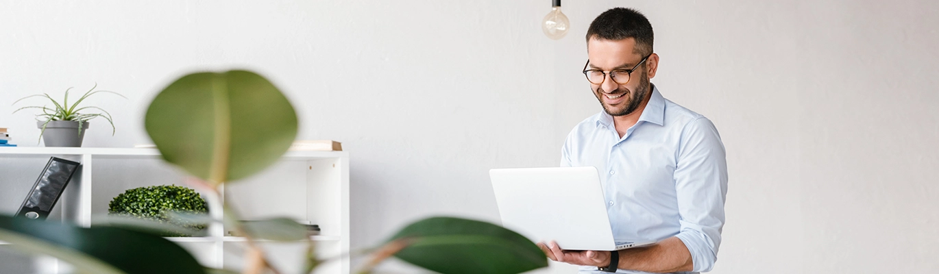 A Corporate employee with a laptop in hand, looking to it with a smiling face