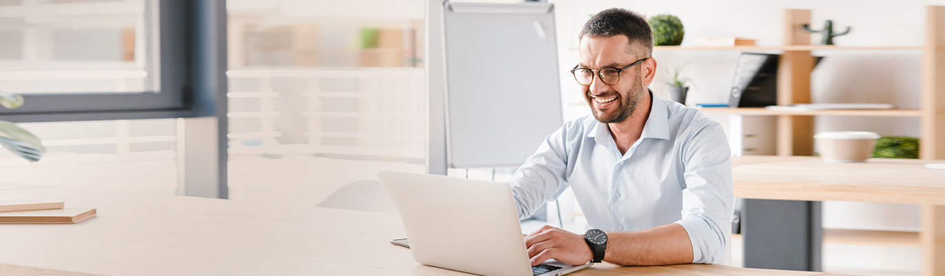 A cloud professional is looking at a laptop screen and smiling