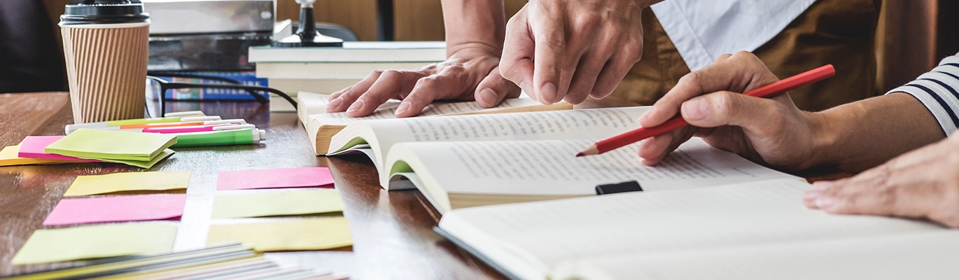 professional teaching his student for exam preparation with books