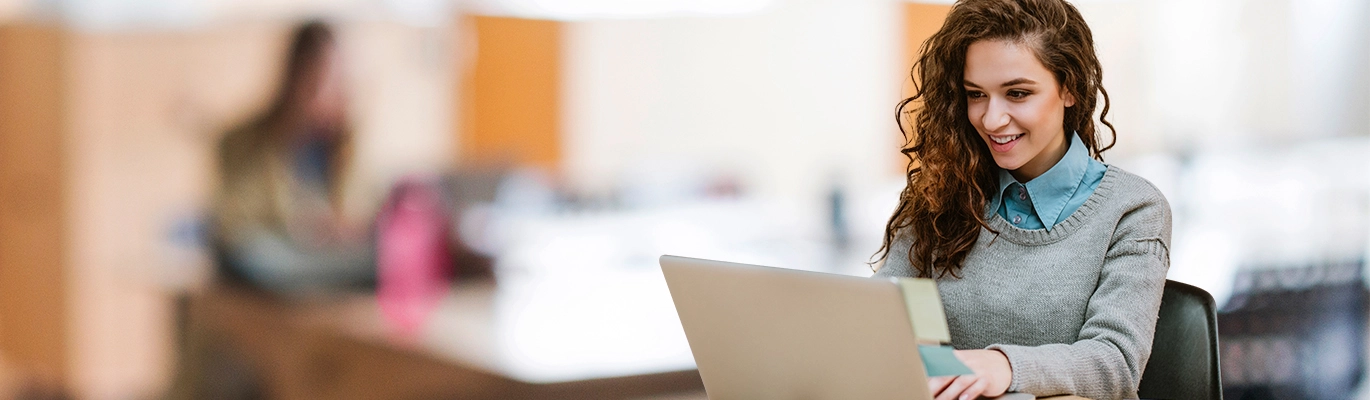 A student working on a laptop and smiling