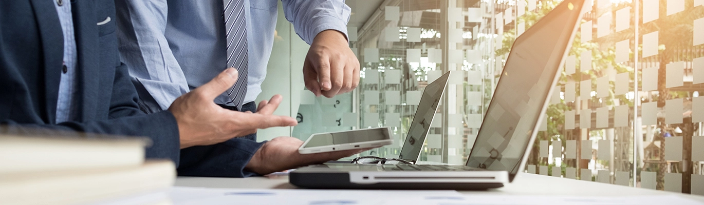 Two professionals working using two laptops and a tablet