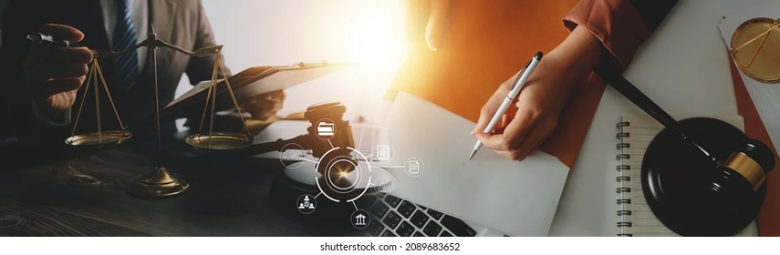 Saudi Labour Law students sitting infront of a computer and smiling , others two discussing together at office enivironment with looking in computer